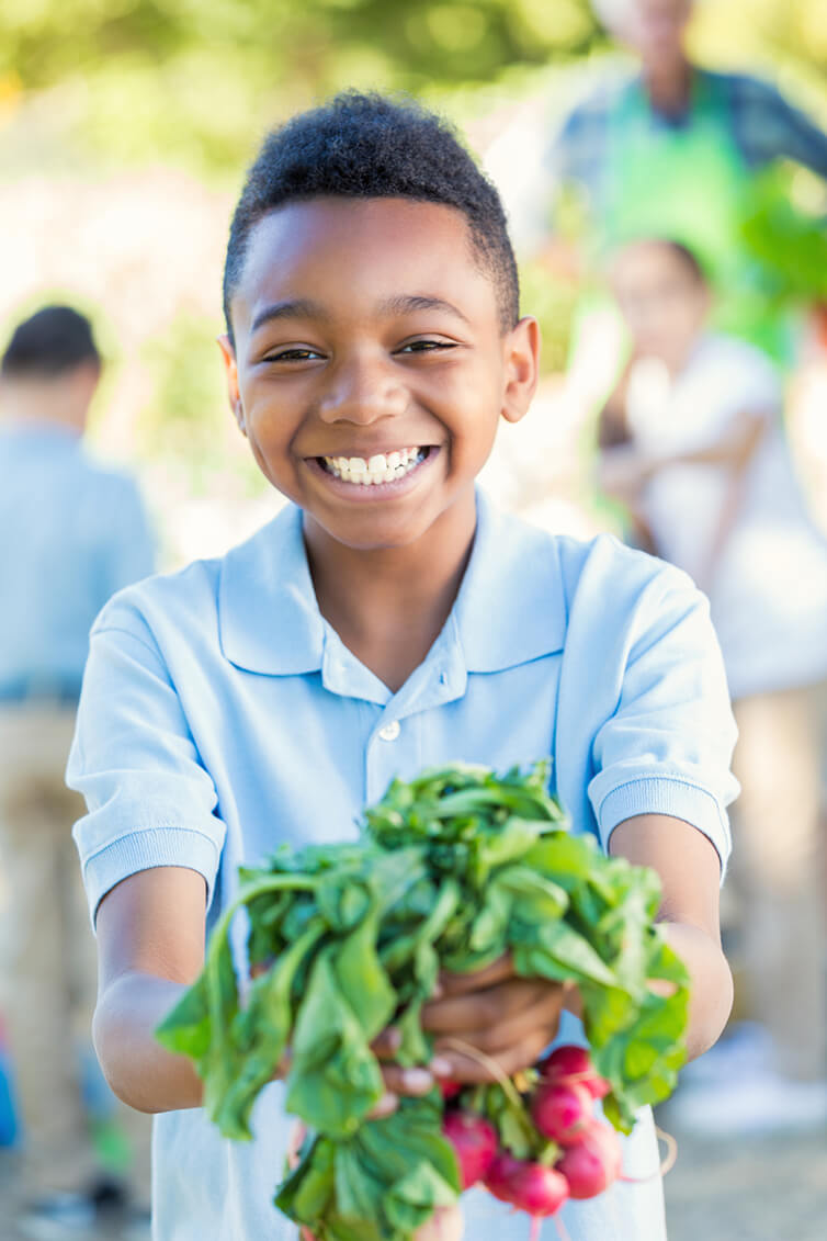 Young boy holding fresh vegetables smiling